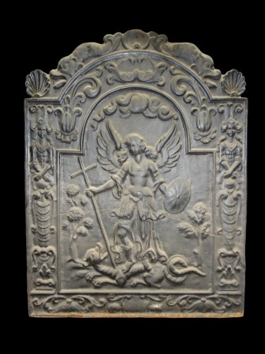 Haardplaat met reliëfdecor van engel staand op dier, die zij doorboord met het kruis